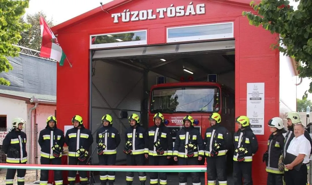 Egyesületünk tagjai védőfelszerelésben a tűzoltószertár előtt, mögöttük a tűzoltóautó